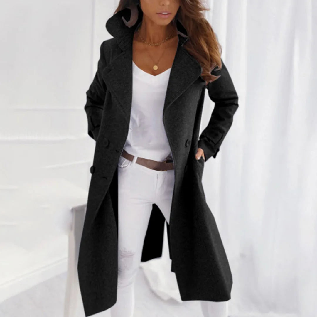 Black double-breasted wool-blend trench coat with wide lapels, worn open over a white top and jeans