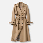 Beige double breasted trench coat with wide lapels, tie belt and checked lining visible at the hem, front view