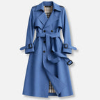 Blue double breasted trench coat with buckled cuffs, tie belt and checked lining showing at the hem