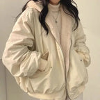 Close-up front view of an oversized beige double-layer jacket with a fleece-lined hood, worn open over a cream polo neck jumper