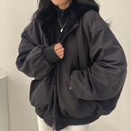 Front view of a black double-layer hooded jacket with faux-fur lining, worn zipped partway with hands tucked into the pockets