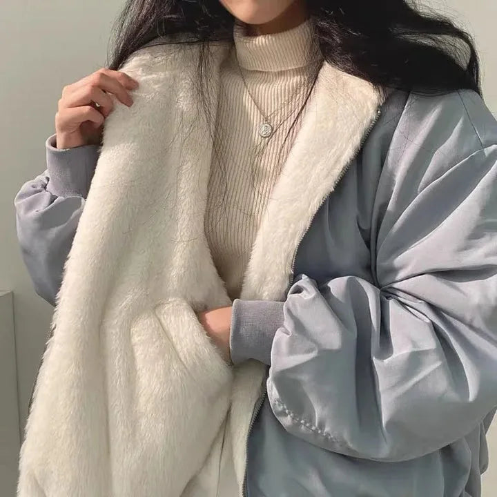 Detail shot of a blue-grey jacket held open to show its plush cream faux-fur lining and contrasting satin-look outer shell