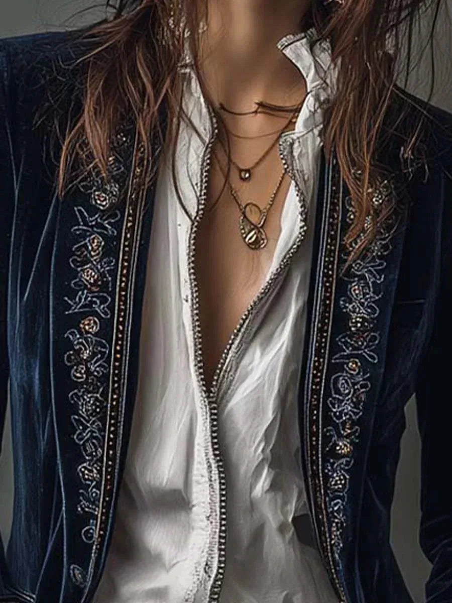 Close-up of embroidered velvet lapel trim with beaded edging worn over a ruffled white blouse