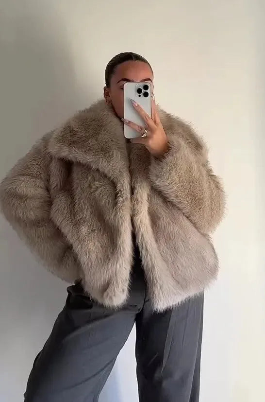 Front view of the faux fur coat showing the wide collar framing the neckline against sunglasses and dark lipstick