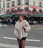 Woman adjusting her hair while wearing the cropped black faux fur coat over a sheer lace bodysuit
