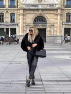Full-length view of black faux fur coat styled with black leather trousers, loafers and a black handbag