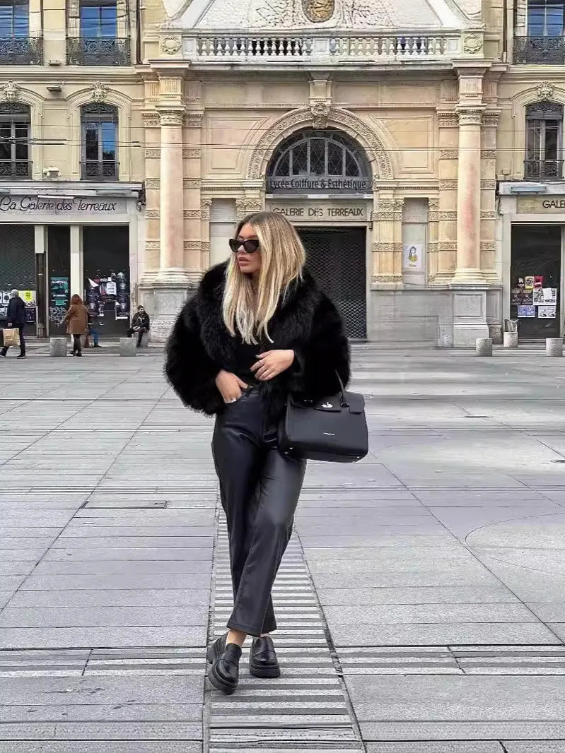 Full-length view of black faux fur coat styled with black leather trousers, loafers and a black handbag