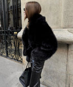 Side view highlighting the deep plush pile and relaxed oversized fit of the black faux fur coat
