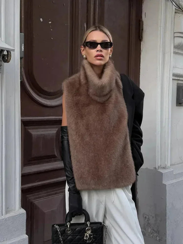 Model in a brown faux fur cropped gilet layered over a black blazer with black leather gloves