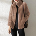 Close-up of a light taupe faux fur jacket showing the soft textured pile and drawstring collar detail