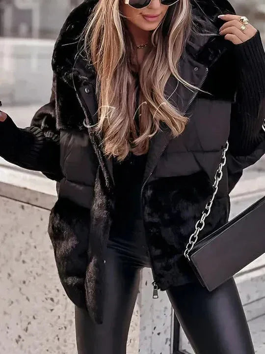 Black hooded puffer jacket with faux fur panels, shown open over a black outfit and clutch bag