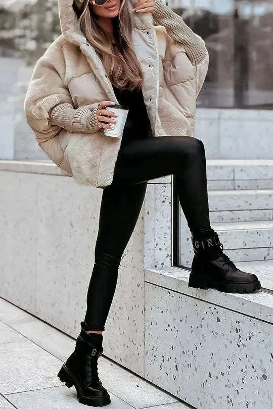 Beige oversized puffer jacket paired with black trousers and studded ankle boots on steps