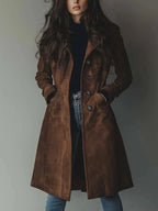 Front view of brown faux suede trench coat worn open over a black jumper and jeans, showing tailored collar and buttons
