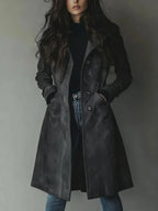 Front view of the coat in dark grey faux suede, buttoned partway open over black knitwear and jeans