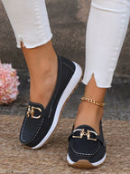 Black loafer with gold horsebit buckle and white platform sole shown from above on stone paving