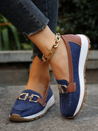 Navy denim loafer with tan leather trim and gold buckle, paired with cropped denim trousers