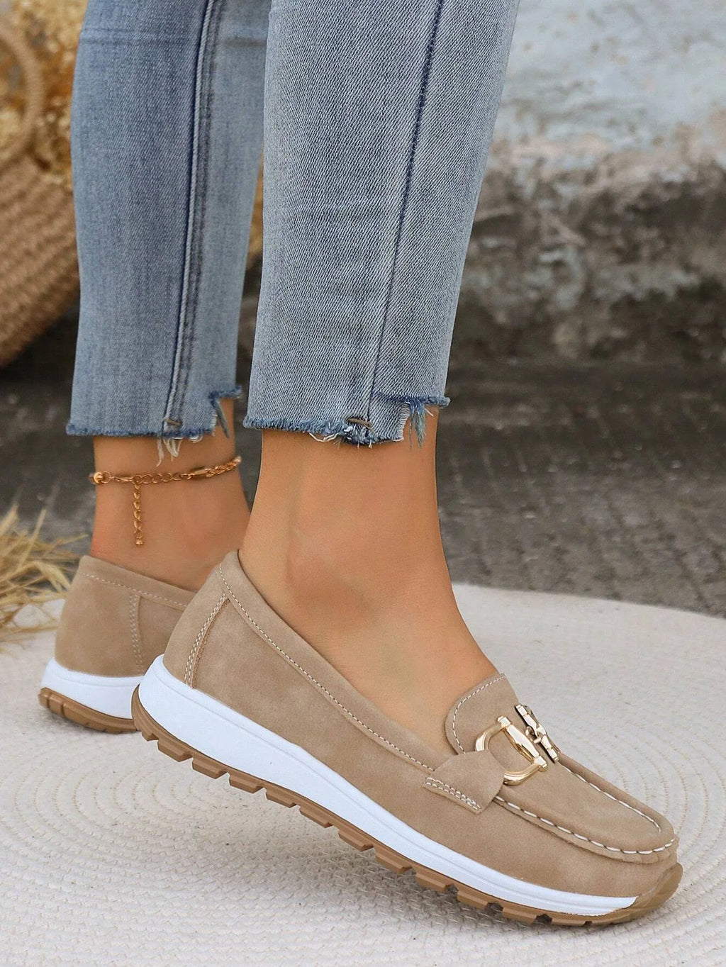 Taupe suede loafer with gold chain hardware and chunky platform sole on woven placemat