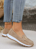 Taupe suede loafer with gold chain hardware and chunky platform sole on woven placemat