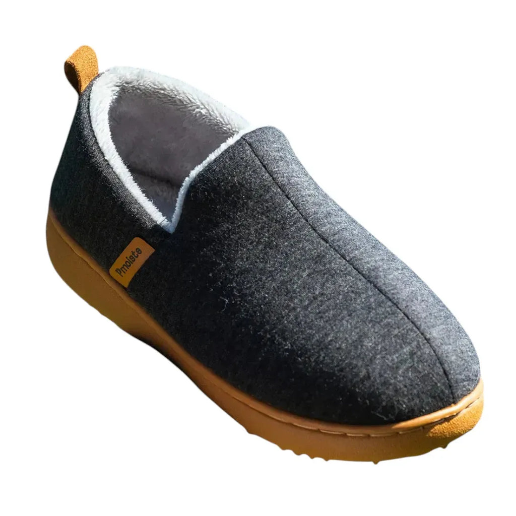 Angled view of a black slip-on house shoe showing the soft grey fleece lining and tan heel loop