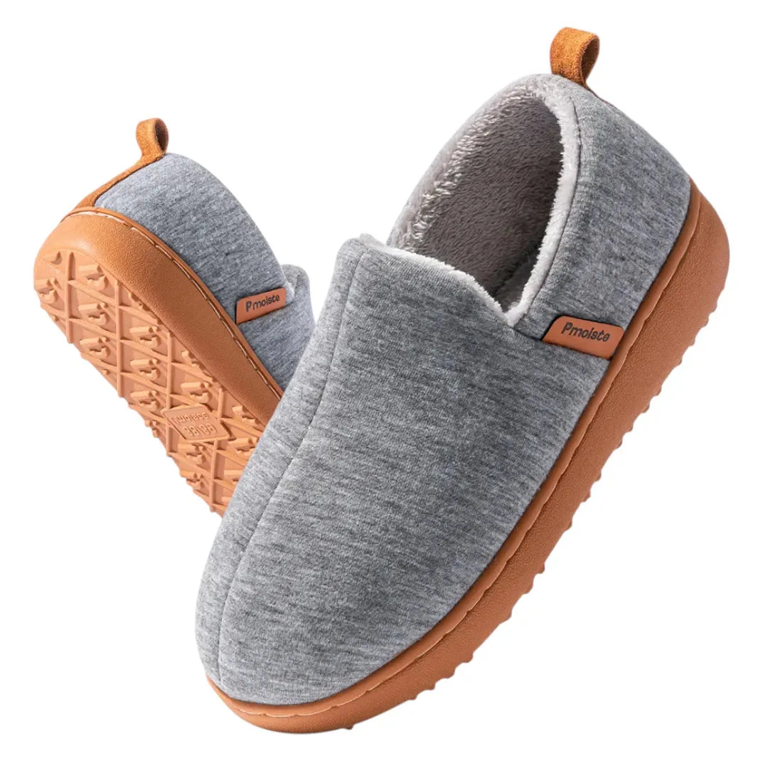 Close-up of the textured tan rubber outsole on a dark grey fleece lined slip-on slipper