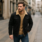 Man wearing a dark jacket with sherpa collar over a mustard jumper and dark trousers