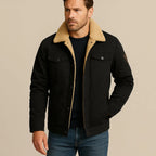 Man wearing a black trucker jacket with cream sherpa collar layered over a navy jumper