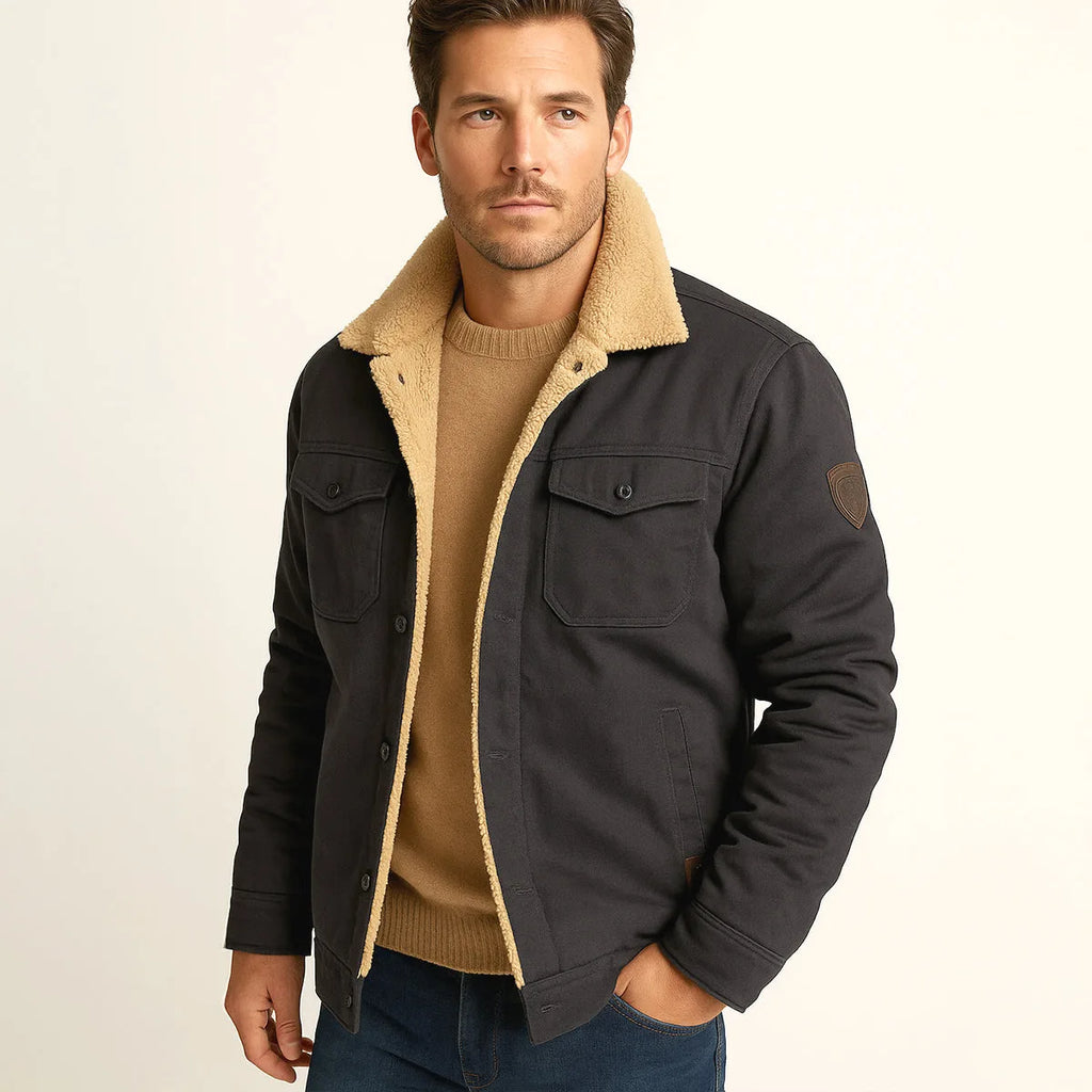 Man wearing a dark charcoal jacket with sherpa collar and dark denim trousers