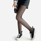 Side view of sheer black tights with a leather-look skirt, mini bag and black platform trainers