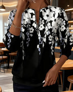 Close-up front view of black floral print zip-neck jumper with white and grey flowers cascading from the shoulders