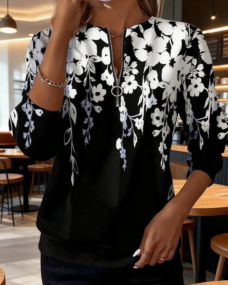 Close-up front view of black floral print zip-neck jumper with white and grey flowers cascading from the shoulders