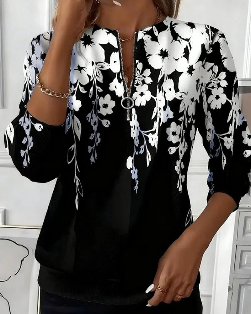 Model wearing the black and white floral print sweatshirt with a silver half-zip pull and layered necklaces