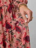 Close-up of pink floral chiffon fabric showing tiered skirt seam and gold bangle bracelets