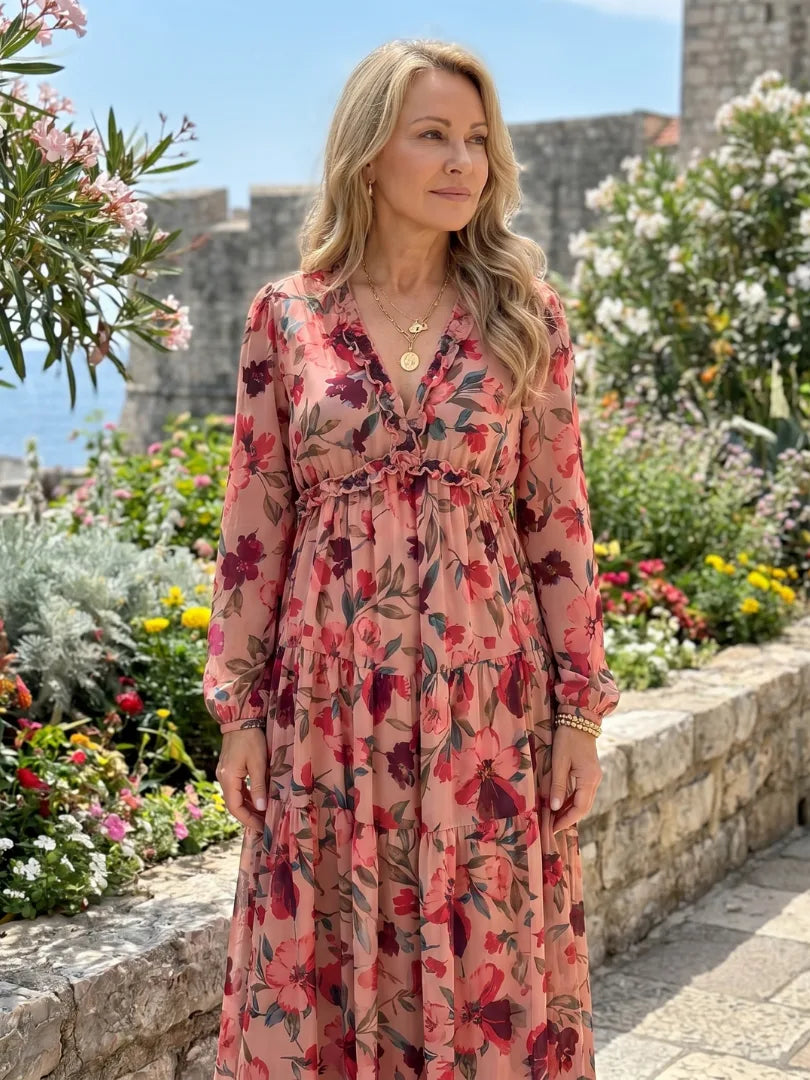 Pink floral maxi dress styled outdoors with gold layered necklaces against a garden backdrop