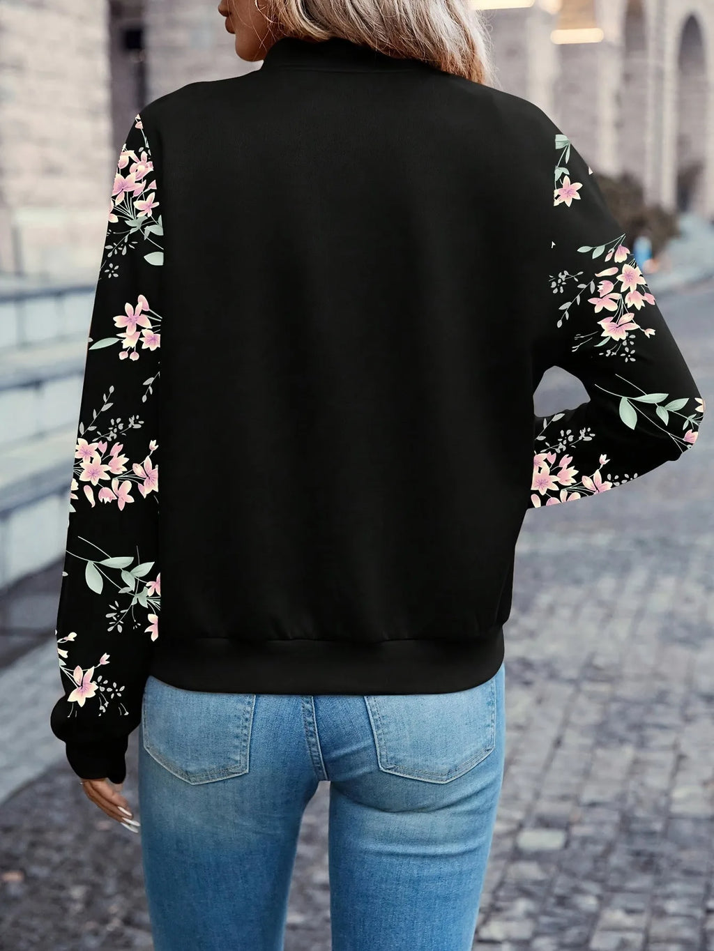 Back view showing the black bomber jacket's floral sleeve print and ribbed hem and collar