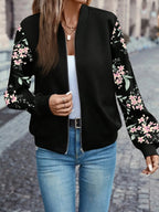 Side angle of the black floral bomber jacket with hand in the side pocket, worn with denim