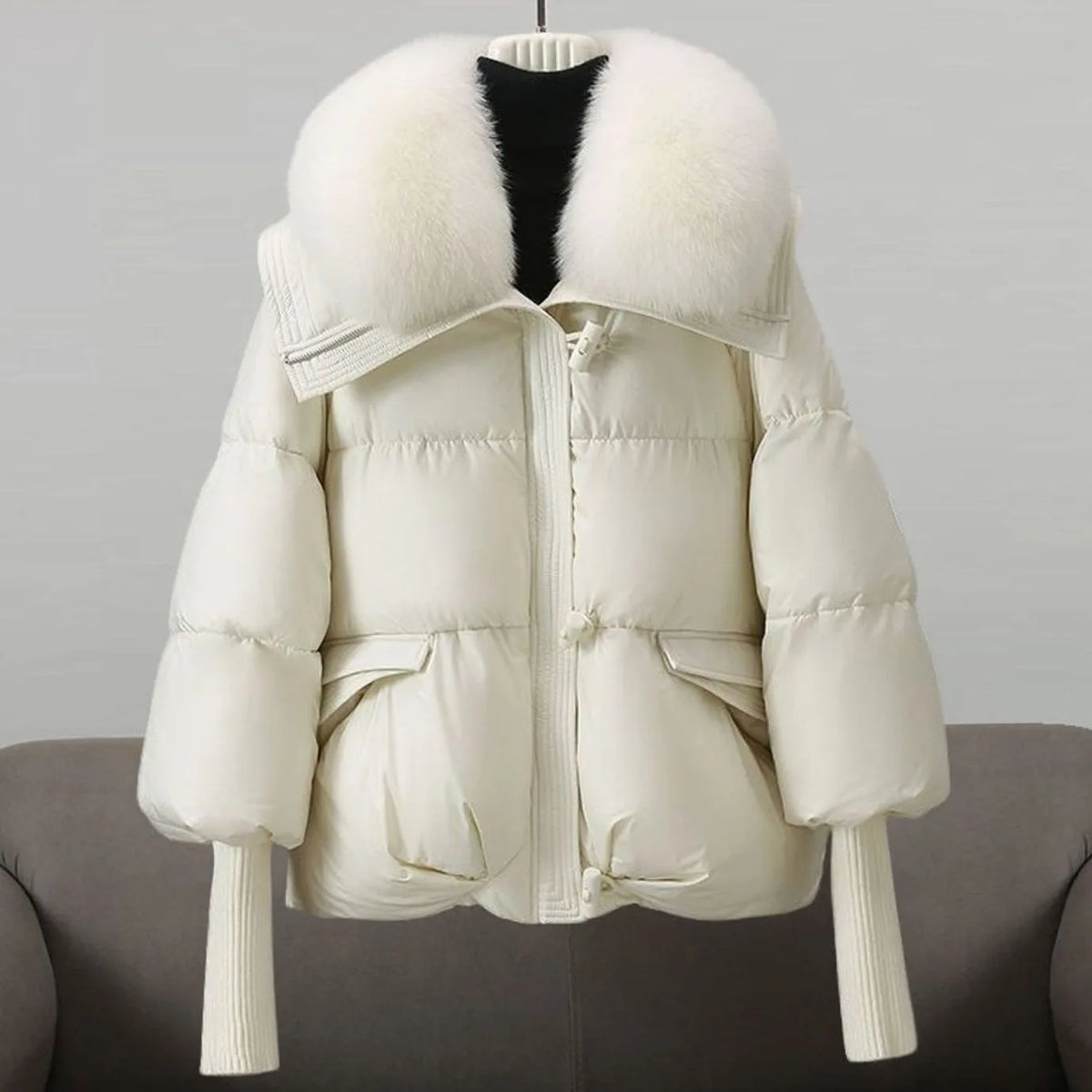 Cream white cropped puffer jacket displayed on a hanger, showing the plush white fur collar and quilted body