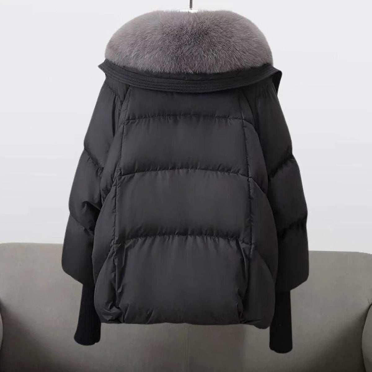 Back view of a black cropped puffer jacket showing the grey fur-trimmed hood and horizontal quilted panels