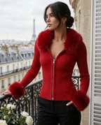 Woman in a red ribbed knit zip cardigan with plush faux fur collar and cuffs, standing on a Paris balcony
