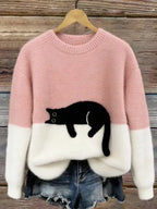 Pink and white two-tone jumper with a soft black cat patch resting at the colour-block seam