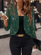 Green sequin cropped cardigan jacket with sheer sparkle finish styled over a black top and denim