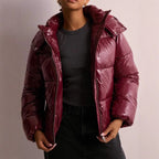 Front view of a burgundy high-shine puffer jacket worn open over a grey top, showing quilted panels and zip