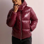 Close-up of the burgundy glossy puffer jacket's adjustable hood and silver zip, worn with hood framing the face