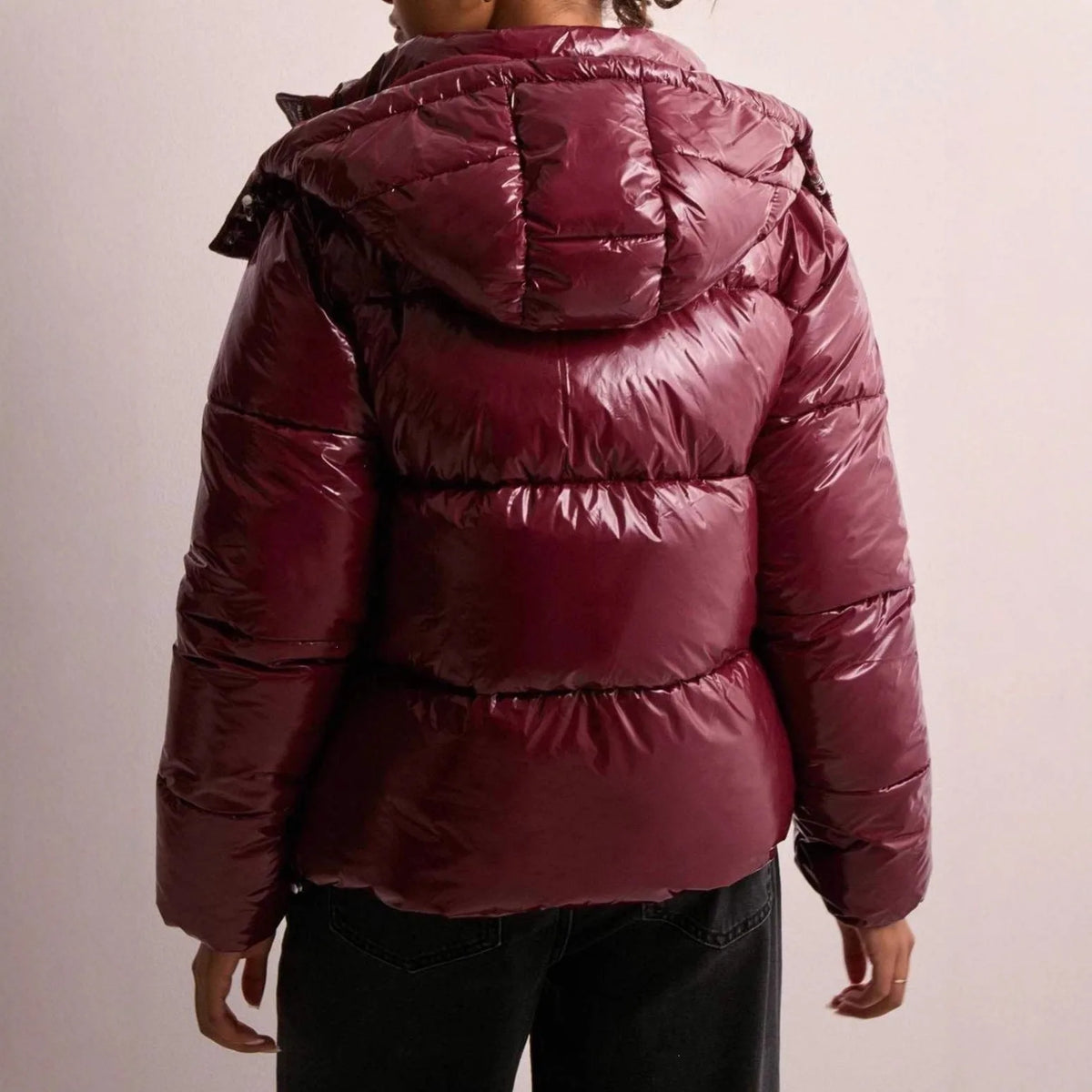 Back view of the burgundy puffer jacket showing quilted panelling and attached hood with press-stud closures