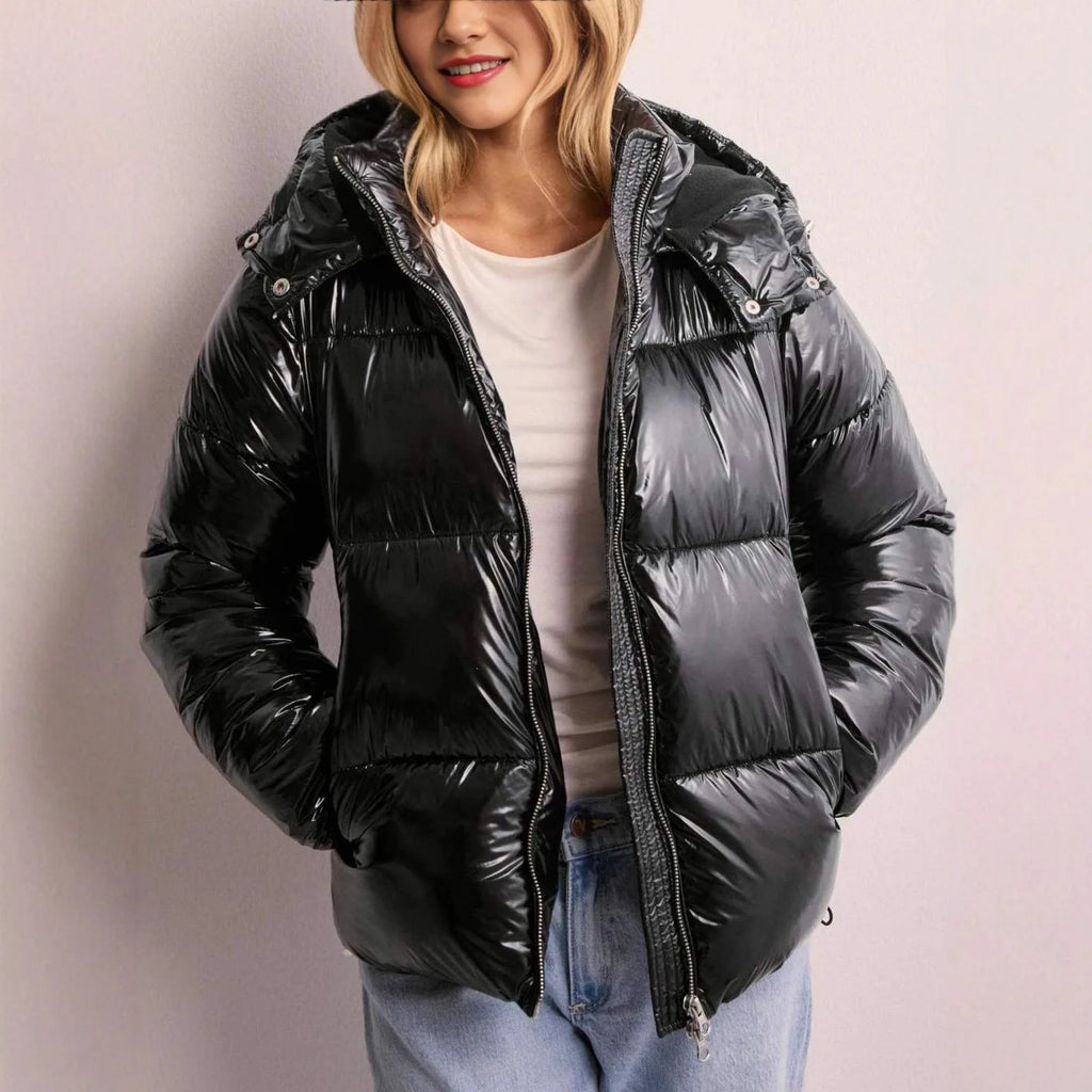 Front view of a black high-shine puffer jacket worn open over a white top with jeans, hood up and zipped detail