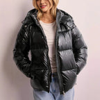 Front view of a black high-shine puffer jacket worn open over a white top with jeans, hood up and zipped detail