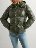 Front view of an olive green glossy puffer jacket with hood up, worn with light wash jeans