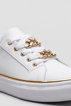 Close-up of the gold chain-link lace detail threaded through the front eyelets of a white trainer