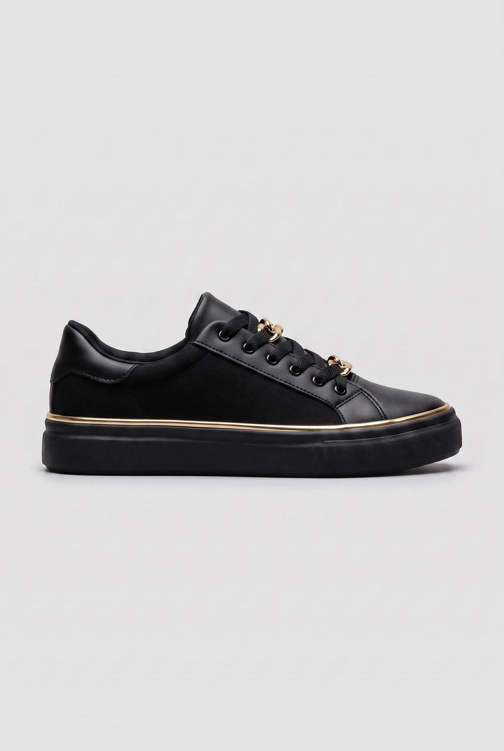 Side view of a black trainer with gold chain-link lace detail and a slim gold trim around the black sole