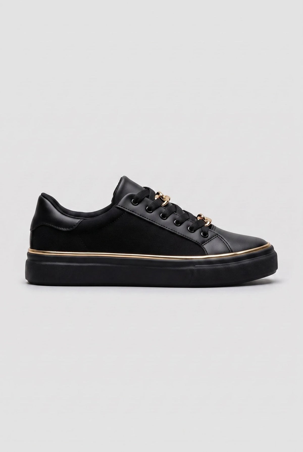 Side view of a black trainer with gold chain-link lace detail and a slim gold trim around the black sole