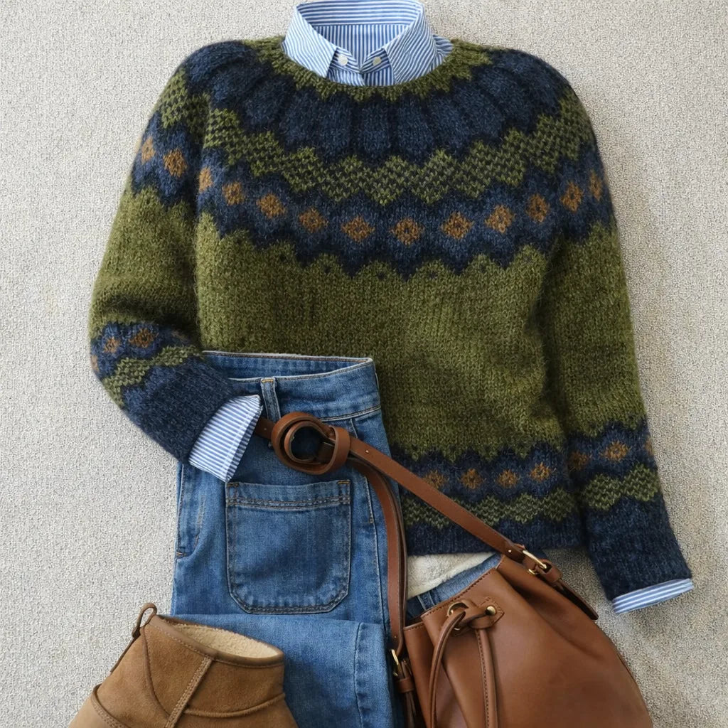 Flat lay of an olive green and navy Nordic-pattern knit jumper styled with a striped shirt, jeans, tan bucket bag and suede boots.